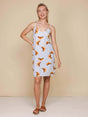 SNURK Croissants Strap Dress Dames model met spaghettibandjes en croissantjesprint in een beige achtergrond.
