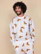 SNURK Croissants Sweater Heren met een man die lacht, bedekt met croissantjes op een lichte achtergrond.