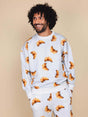 SNURK Croissants Sweater Heren met een man die lacht, bedekt met croissantjes op een lichte achtergrond.