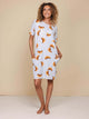 Model in SNURK Croissants T-shirt Dress Dames met croissantprint en praktische zakken, ideaal voor zomerse dagen.
