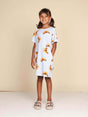 SNURK Croissants T-shirt Dress Kids gedragen door een meisje met een vrolijke uitstraling, gekleed in een jurkje met croissants.