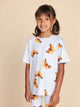 SNURK Croissants T-shirt Kids, kind in T-shirt met croissantjes op een neutrale achtergrond.