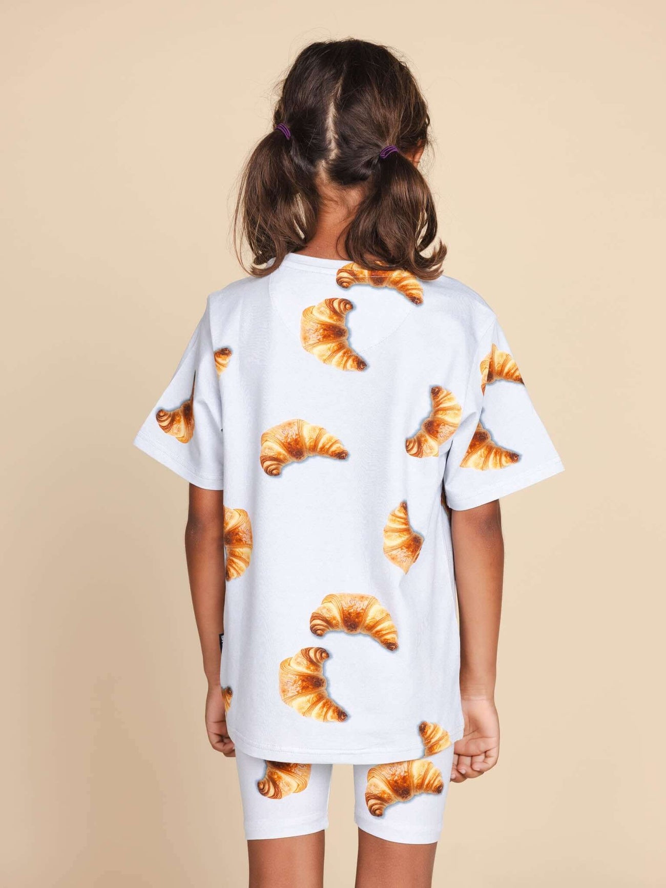 SNURK Croissants T-shirt Kids, kind in T-shirt met croissantjes, achteraanzicht, zachte biologische katoen.