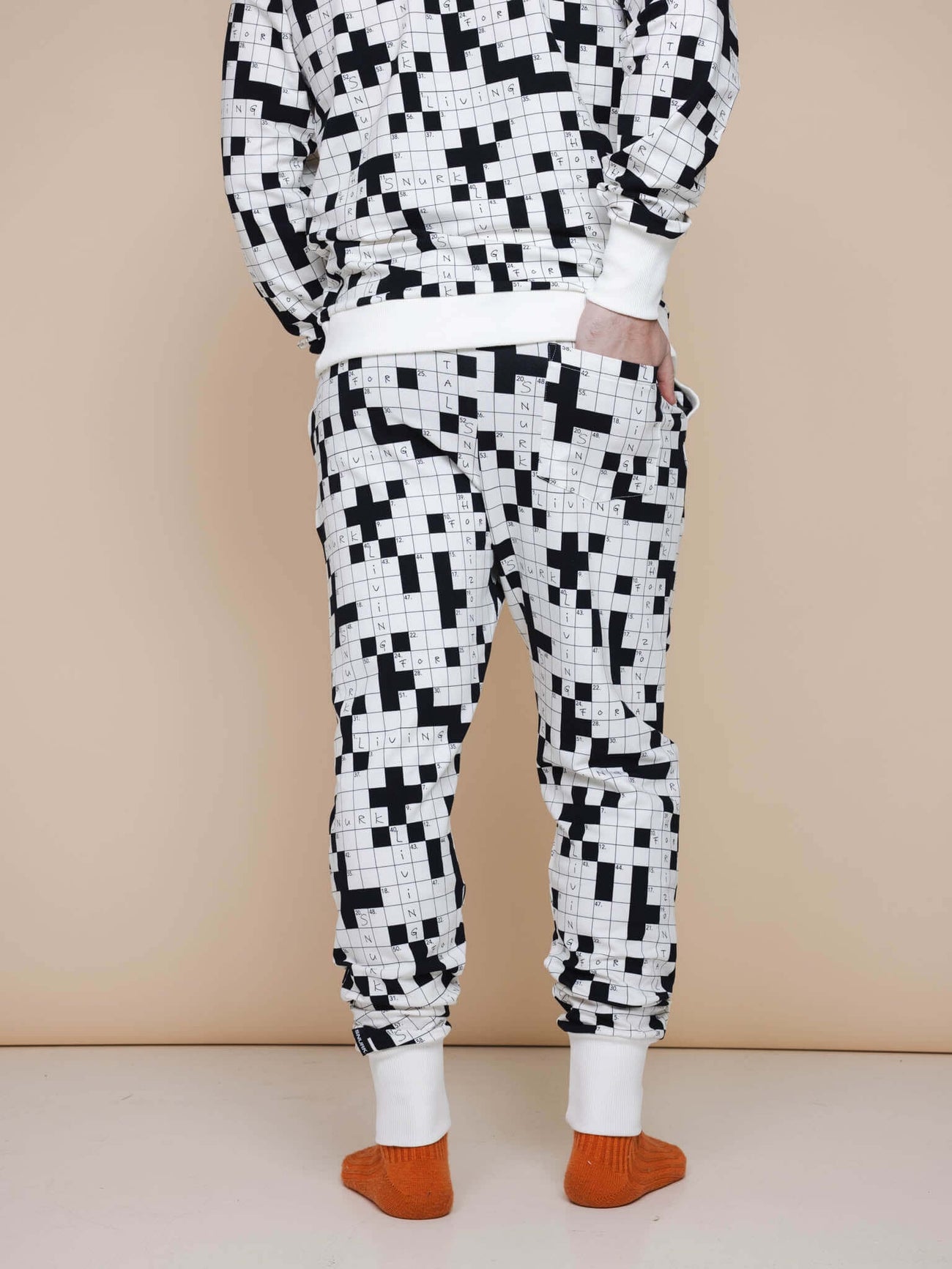 SNURK Crossword Broek Regular Unisex, zwart-witte kruiswoordprint, comfortabele joggingbroek achteraan gezien.