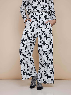 SNURK Crossword Wijde broek Dames, zwarte en witte wijde broek met kruiswoordprint en diepe steekzakken.
