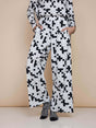 SNURK Crossword Wijde broek Dames, zwarte en witte wijde broek met kruiswoordprint en diepe steekzakken.