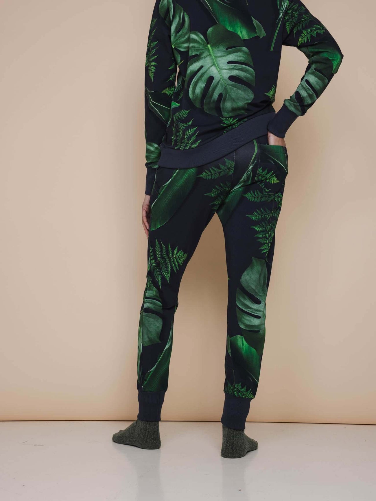 SNURK Dark Forest Broek Regular Unisex met donkergroene bladeren op een antracietgrijze achtergrond.