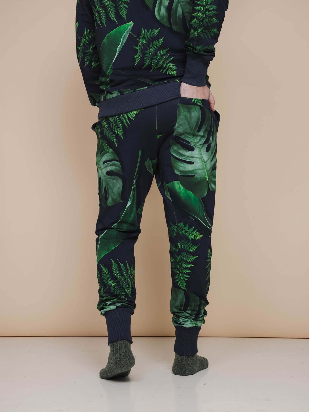 SNURK Dark Forest Broek Regular Unisex met grote donkergroene bladeren op een antracietgrijze achtergrond.
