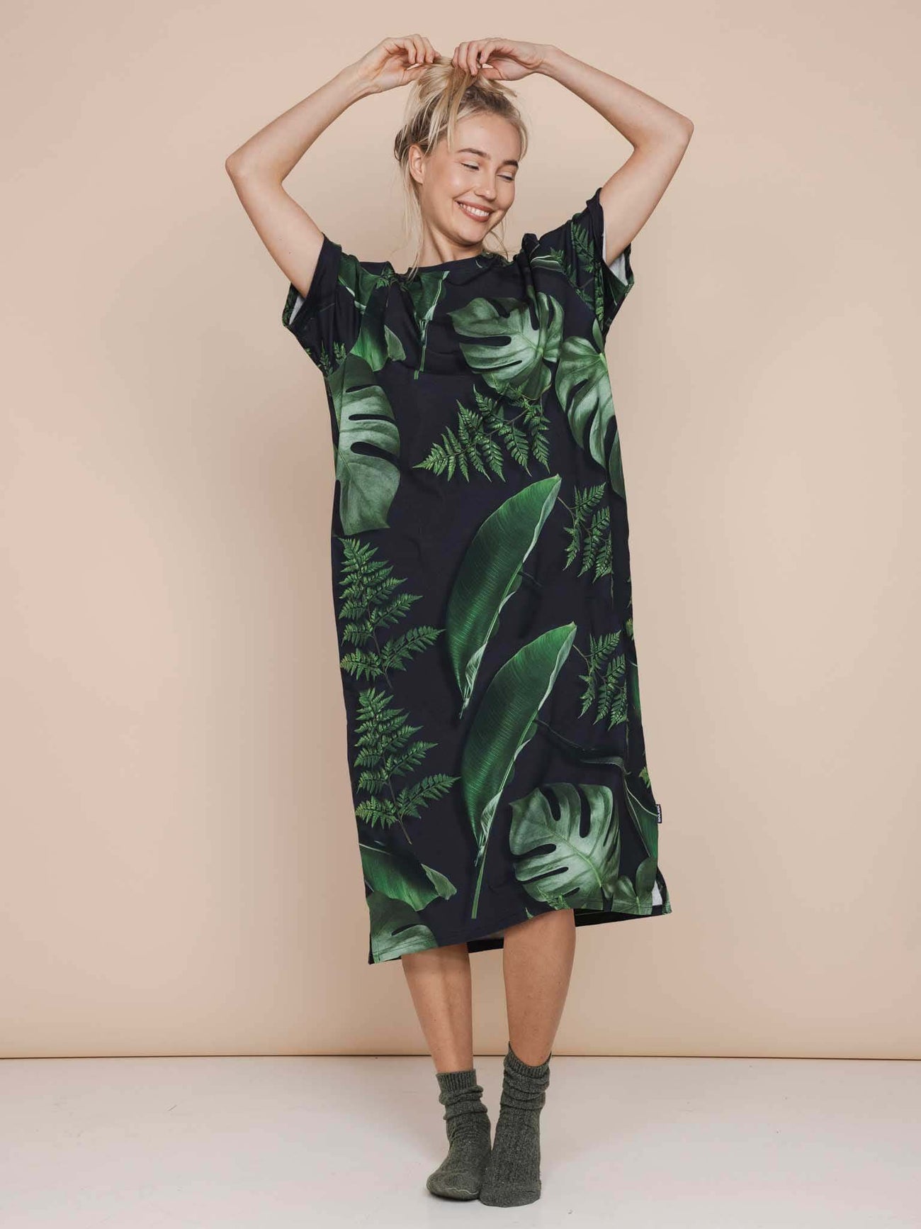 Model in SNURK Dark Forest Relaxed Tee Dress Dames, oversized jurk met grote donkergroene bladeren.