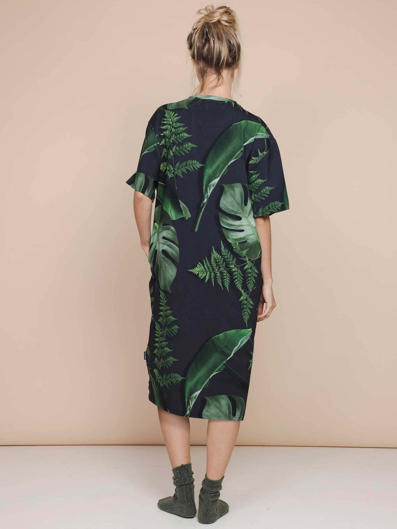 SNURK Dark Forest Relaxed Tee Dress Dames met grote bladeren op donkergroene achtergrond, achterzijde view.