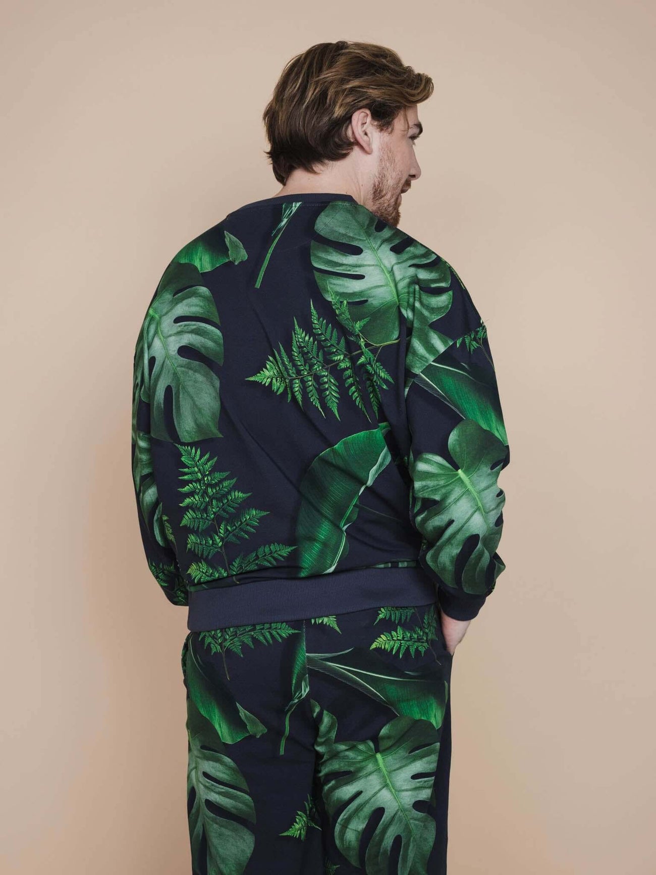 SNURK Dark Forest Sweater Heren met donkergroene bladeren op antracietgrijze achtergrond.