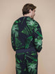 SNURK Dark Forest Sweater Unisex met grote donkergroene bladeren op een antracietgrijze achtergrond.