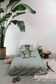 SNURK Dino Green dekbedovertrek op bed met T-Rex en planten, perfect voor stoere kinderkamers.