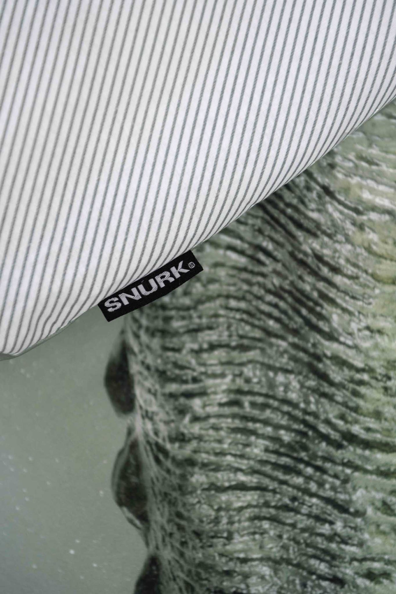 SNURK Dino Green dekbedovertrek met gestreepte kussensloop en T-Rex patroon.