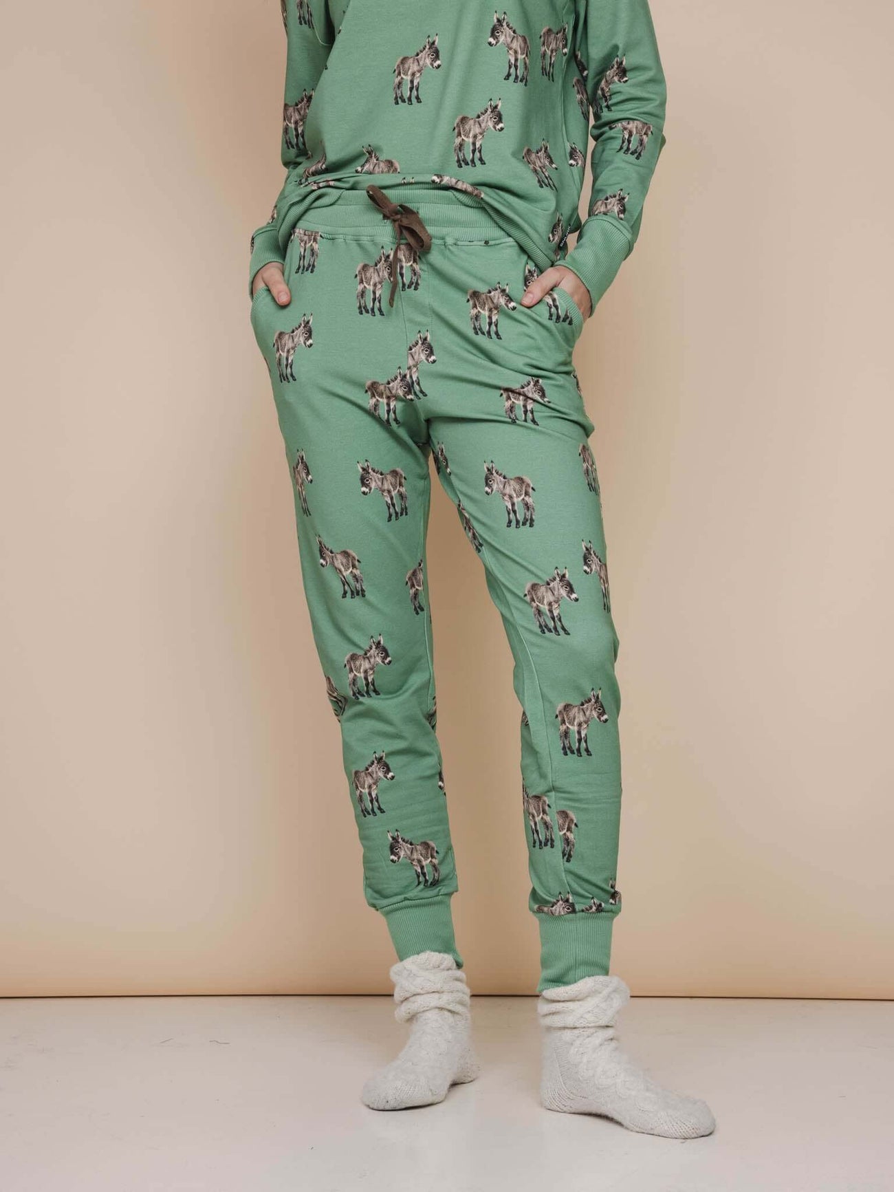 SNURK Donkeys Broek Regular Unisex met schattige baby-ezels op een zachtgroene achtergrond.