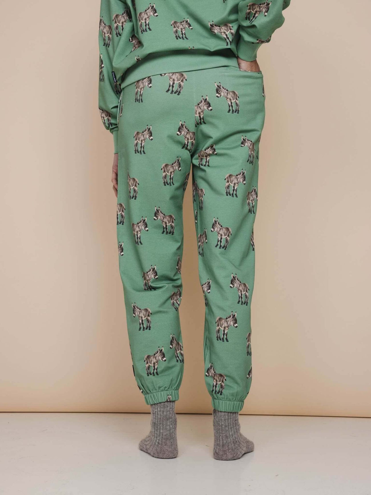 Achteraanzicht van SNURK Donkeys Broek Relaxed Unisex in zachtgroene stof met schattige baby-ezels.