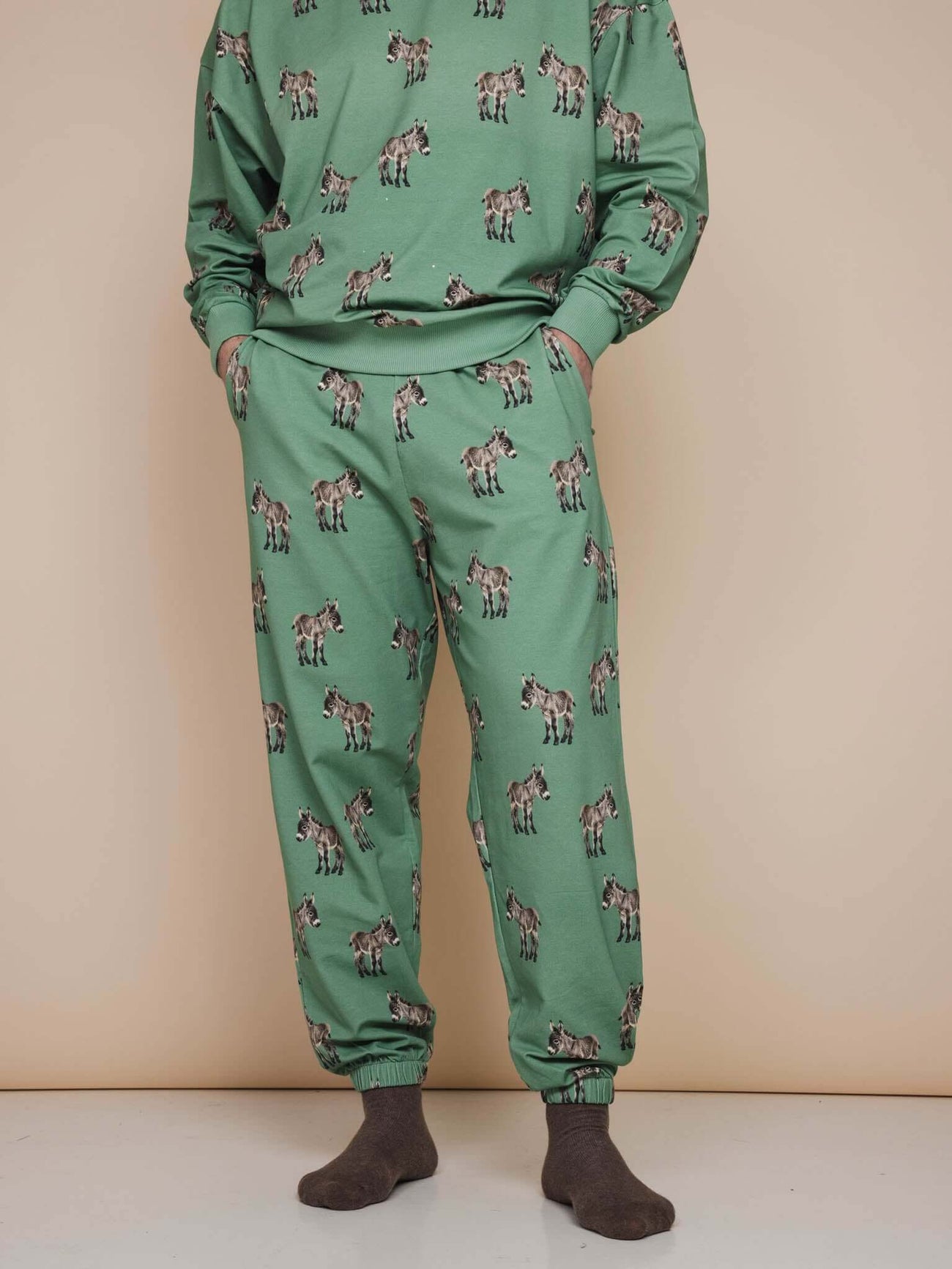 SNURK Donkeys Broek Relaxed Unisex met schattige baby-ezels op zachtgroene achtergrond.