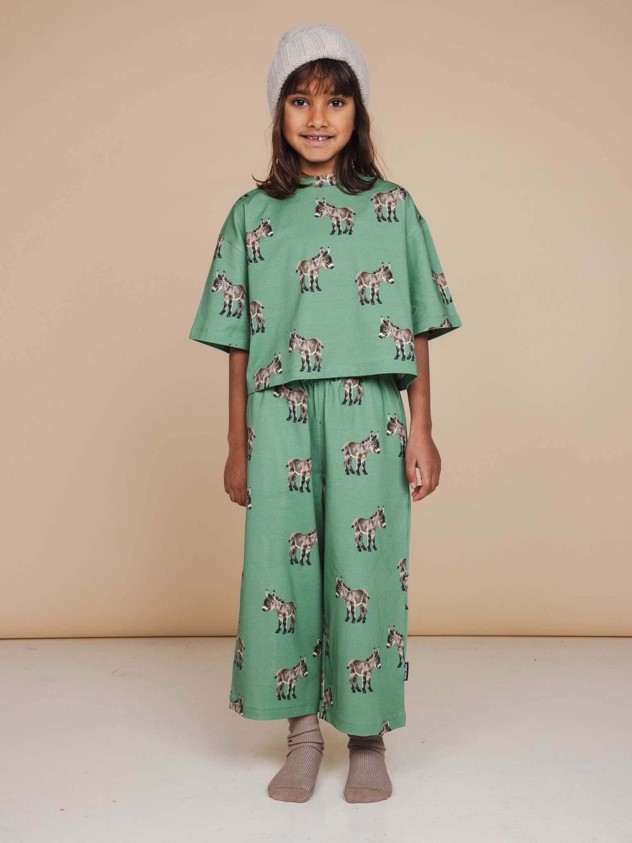 SNURK Donkeys Cropped T-Shirt Kids model wearing a green cropped t-shirt and matching pants with cute donkey print.