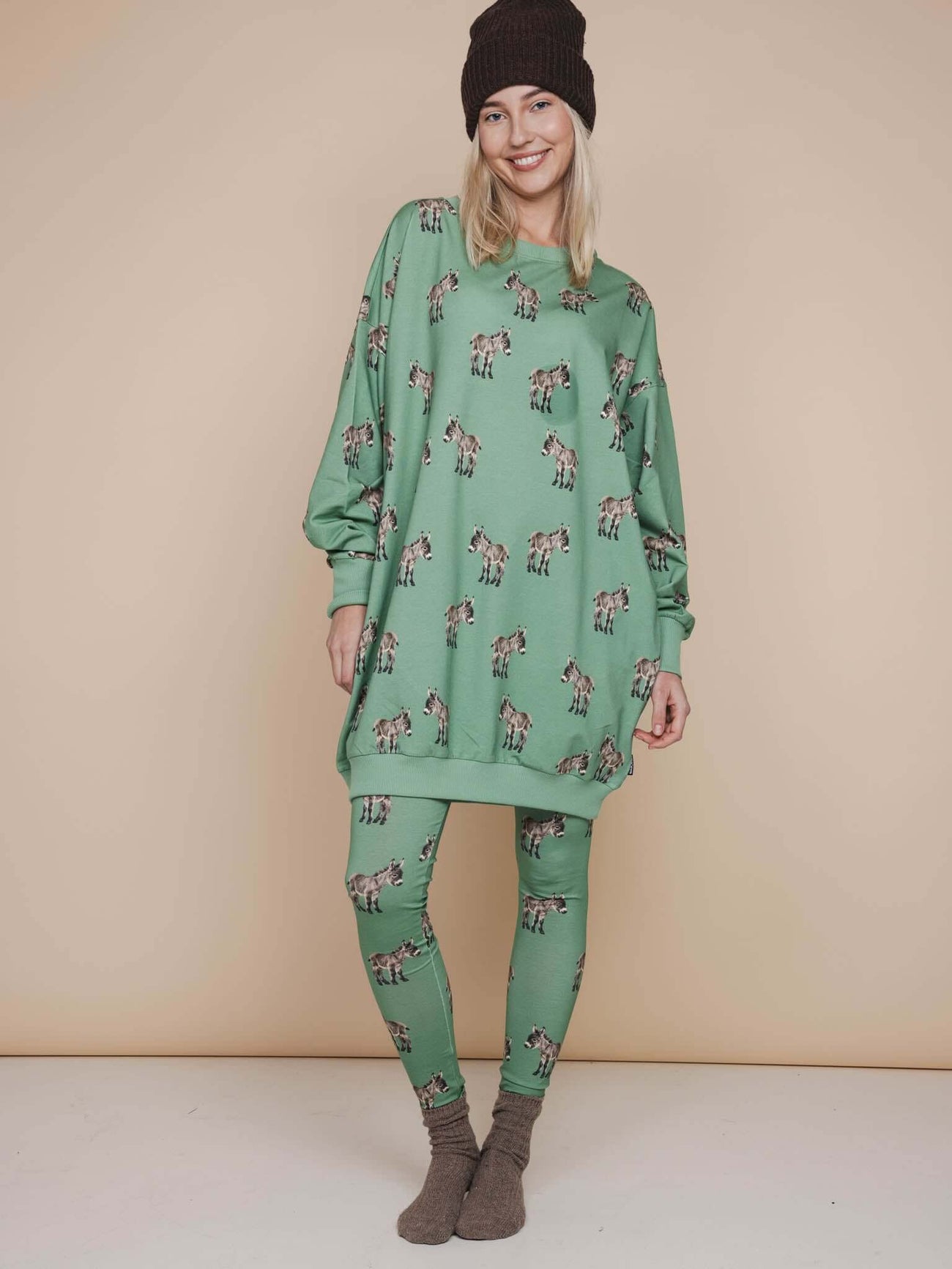 SNURK Donkeys Legging Dames - Model in groene outfit met schattige baby-ezels op een zachte achtergrond.