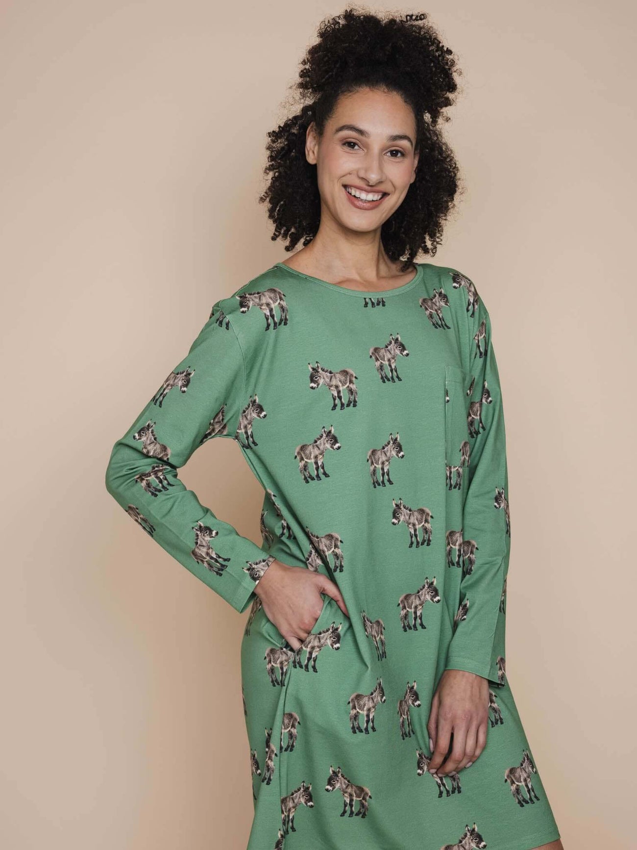 SNURK Donkeys Long Sleeve Dress Dames model met schattige ezels op groene achtergrond, comfortabele pasvorm en lange mouwen.