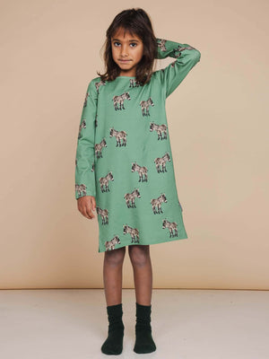 Kind in SNURK Donkeys Long Sleeve Dress Kids met schattige ezels op een zachtgroene achtergrond.