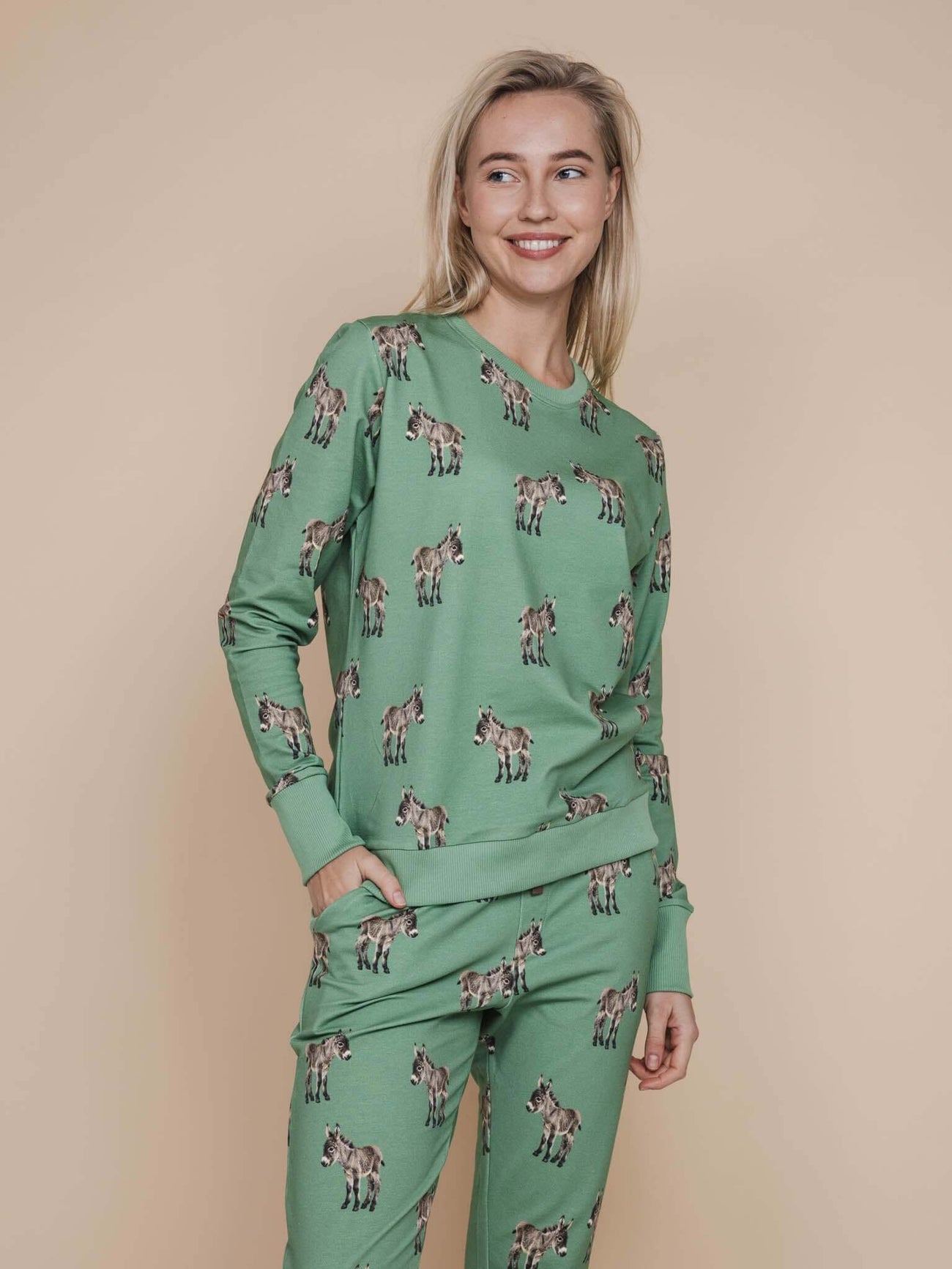 SNURK Donkeys Sweater Dames op een model met schattige baby-ezels op een zachtgroene achtergrond.