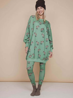 Vrouwelijke model in SNURK Donkeys Sweater Dress Dames met schattige baby-ezels op een zachte groene achtergrond.
