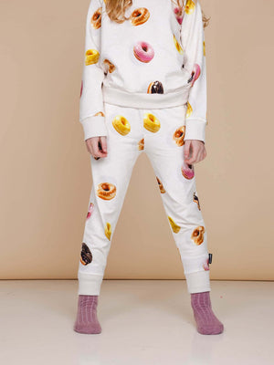 SNURK Donuts Broek Kids met kleurrijke donuts op een zachte beige achtergrond, perfect voor spelen of slapen.