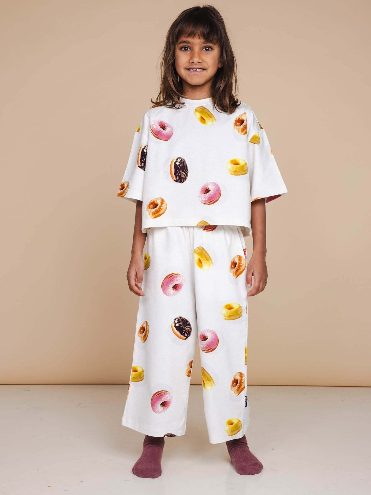 Kind in SNURK Donuts Cropped T-Shirt Kids met vrolijke donutprint, perfect voor speel- en bedtijd.