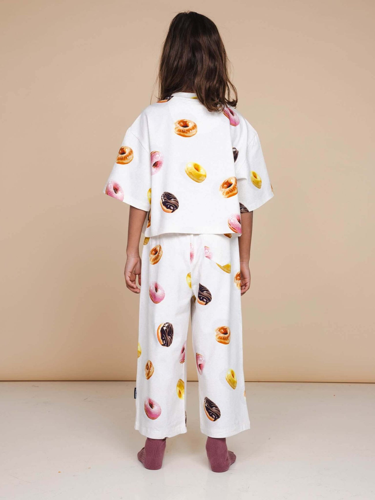 A girl wearing the SNURK Donuts Cropped T-Shirt Kids, showcasing a vibrant donut print in a cropped fit.