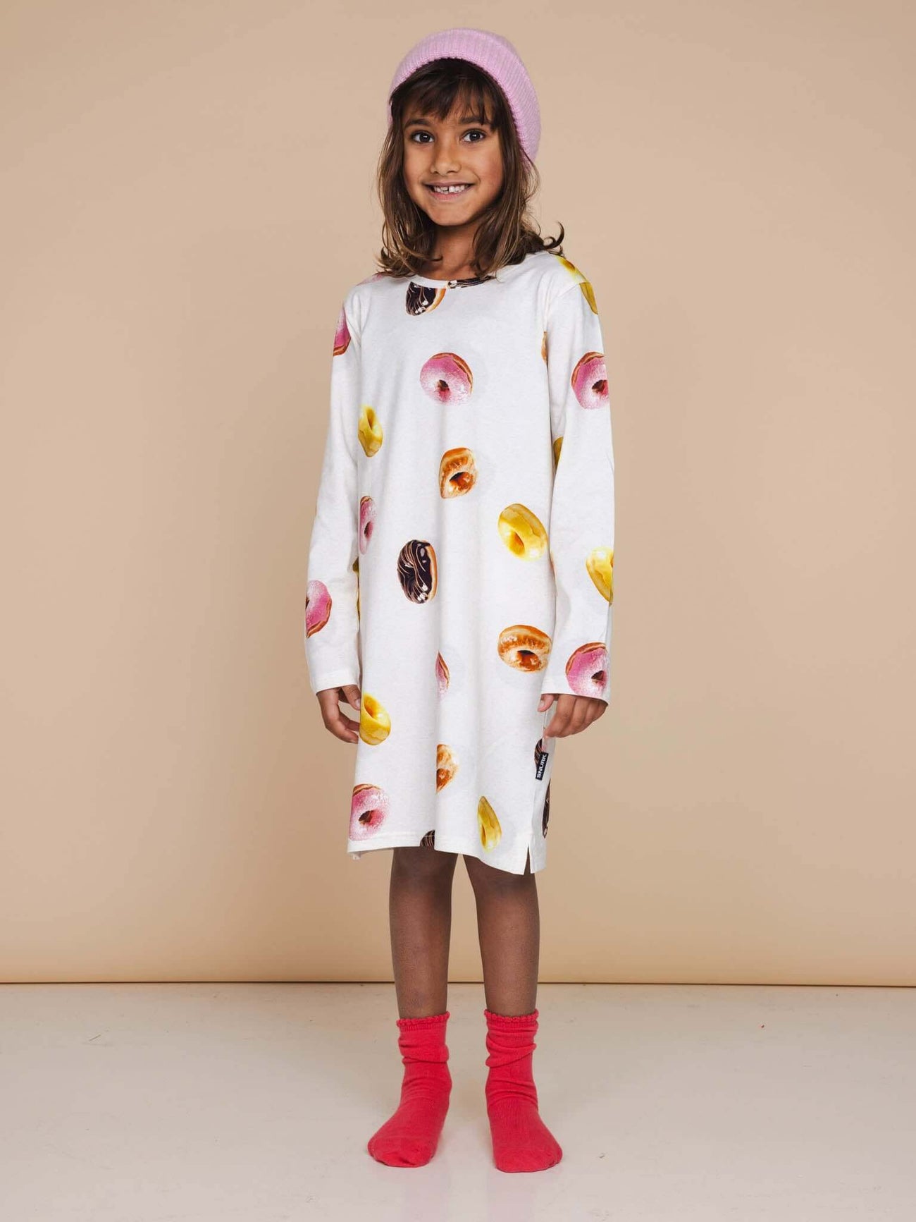 SNURK Donuts Long Sleeve Dress Kids gedragen door een meisje met een roze muts en sokken.