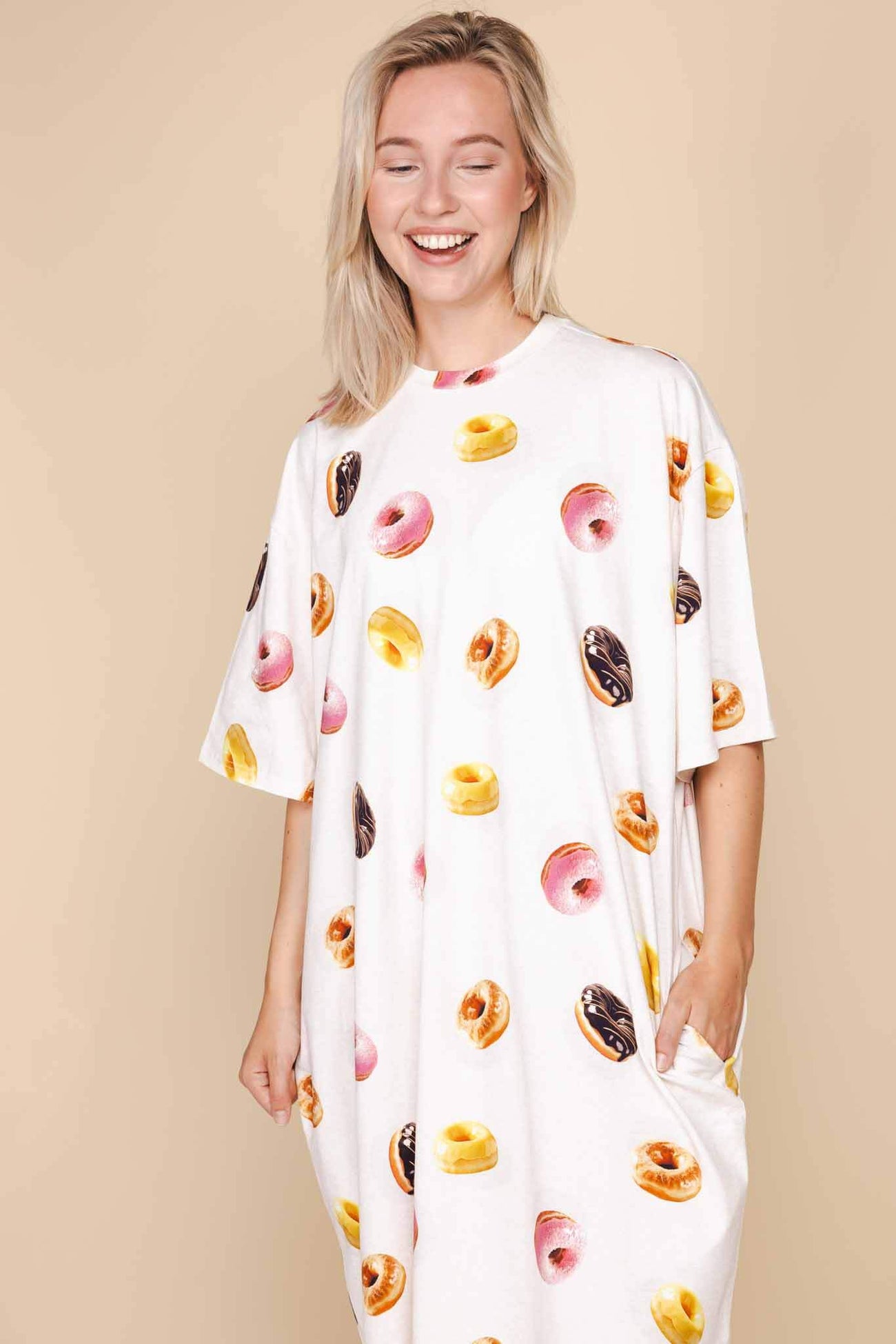 SNURK Donuts Relaxed Tee Dress Dames met kleurrijke donutprint op een model, zachte beige achtergrond.