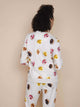 Vrouwelijke model draagt de SNURK Donuts Sweater Dames met kleurrijke donutprint op een beige achtergrond.