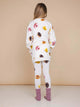 A girl wearing the SNURK Donuts Sweater Dress Kids and matching leggings, showcasing fun donut prints.