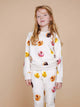 SNURK Donuts Sweater Kids gedragen door een meisje met donutfoto's op een zachte beige achtergrond.