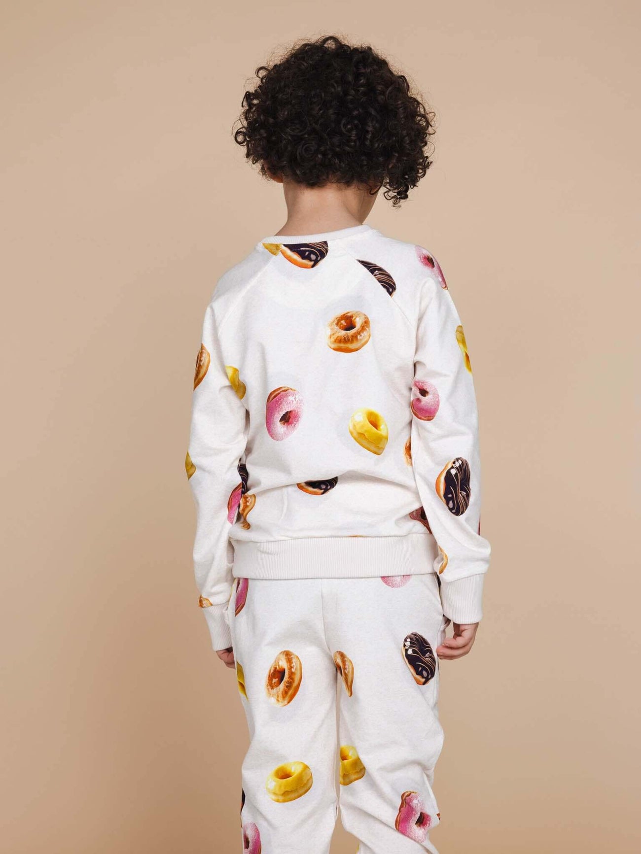 SNURK Donuts Sweater Kids met kleurrijke donuts op een zachte achtergrond, gezien van achteren.
