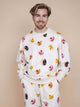 SNURK Donuts Sweater Unisex met kleurrijke donutprint op een zachte beige achtergrond.