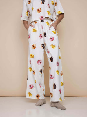 Model draagt SNURK Donuts Wijde broek Dames met kleurrijke donutprint en diepe steekzakken.