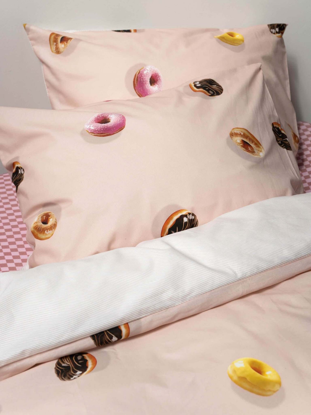 SNURK Donuts dekbedovertrek met kleurrijke donuts op een lichtroze achtergrond voor een trendy slaapkamer.