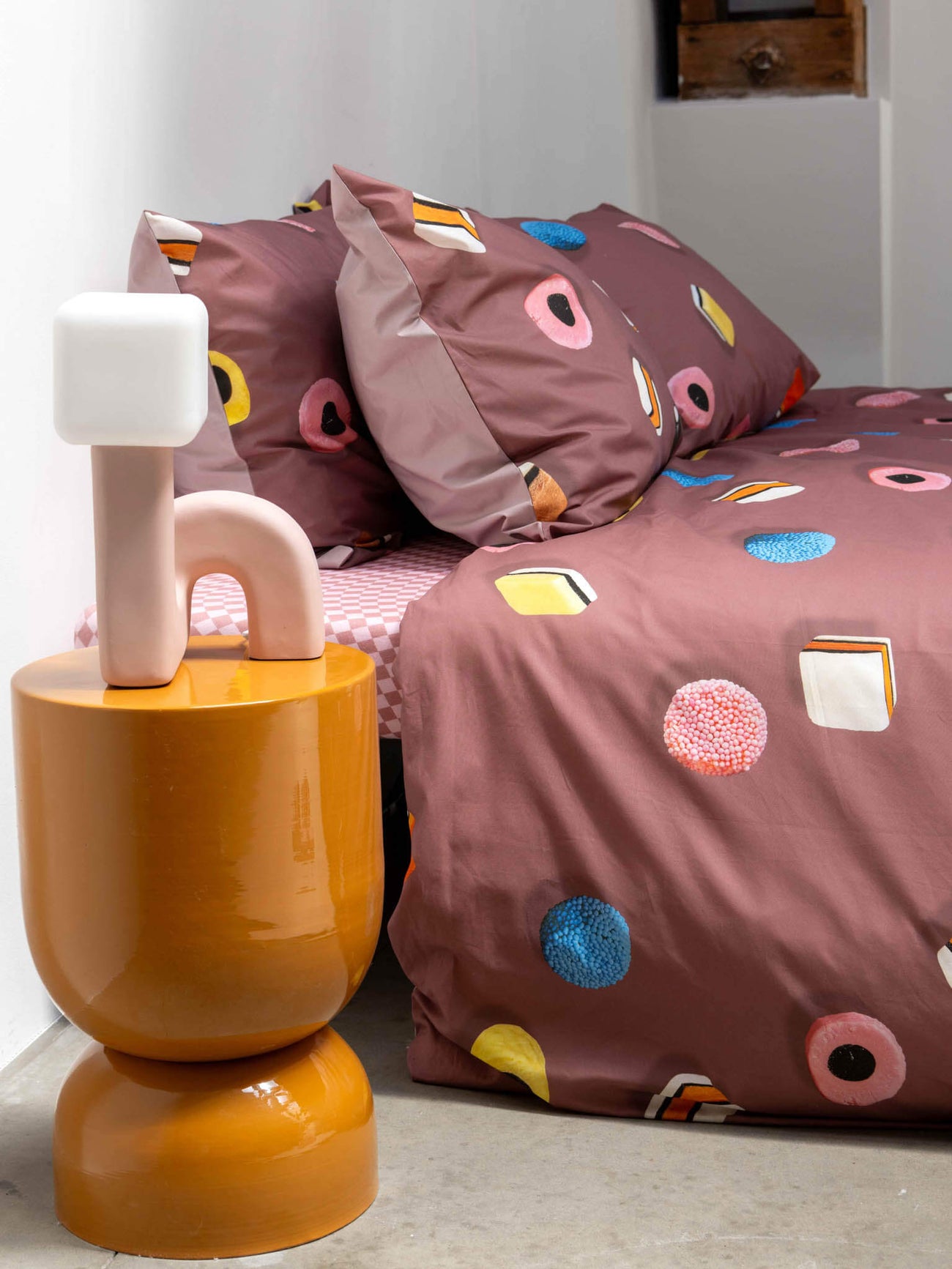 SNURK Drop It dekbedovertrek met kleurrijke patronen en bijpassende kussens op een stijlvolle slaapkamer.