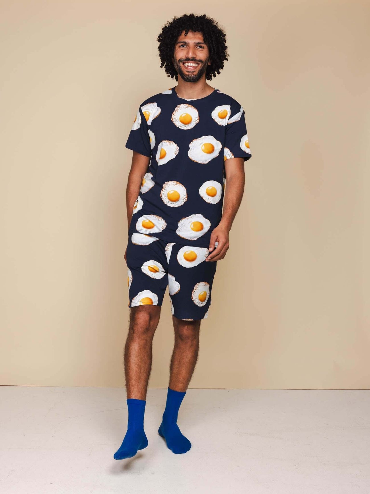 Man in SNURK Eggs Navy Shorts Heren met spiegeleitjesprint, lachend tegen een neutrale achtergrond.
