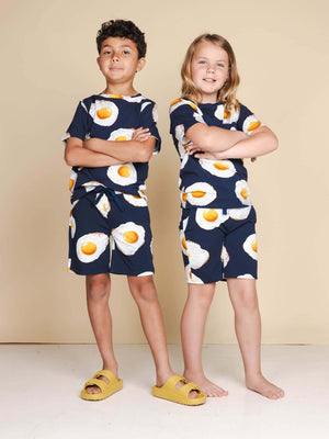 Kinderen in SNURK Eggs Navy T-shirt Kids met spiegeleitjes. Zacht en GOTS-gecertificeerd, ideaal voor bed en school.