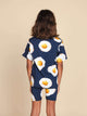 Kind in SNURK Eggs Navy T-shirt Kids met spiegeleitjesprint, achterkant zichtbaar met short.