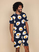 SNURK Eggs Navy T-shirt Unisex met spiegeleitjes patroon op een model met een ontspannen uitstraling.