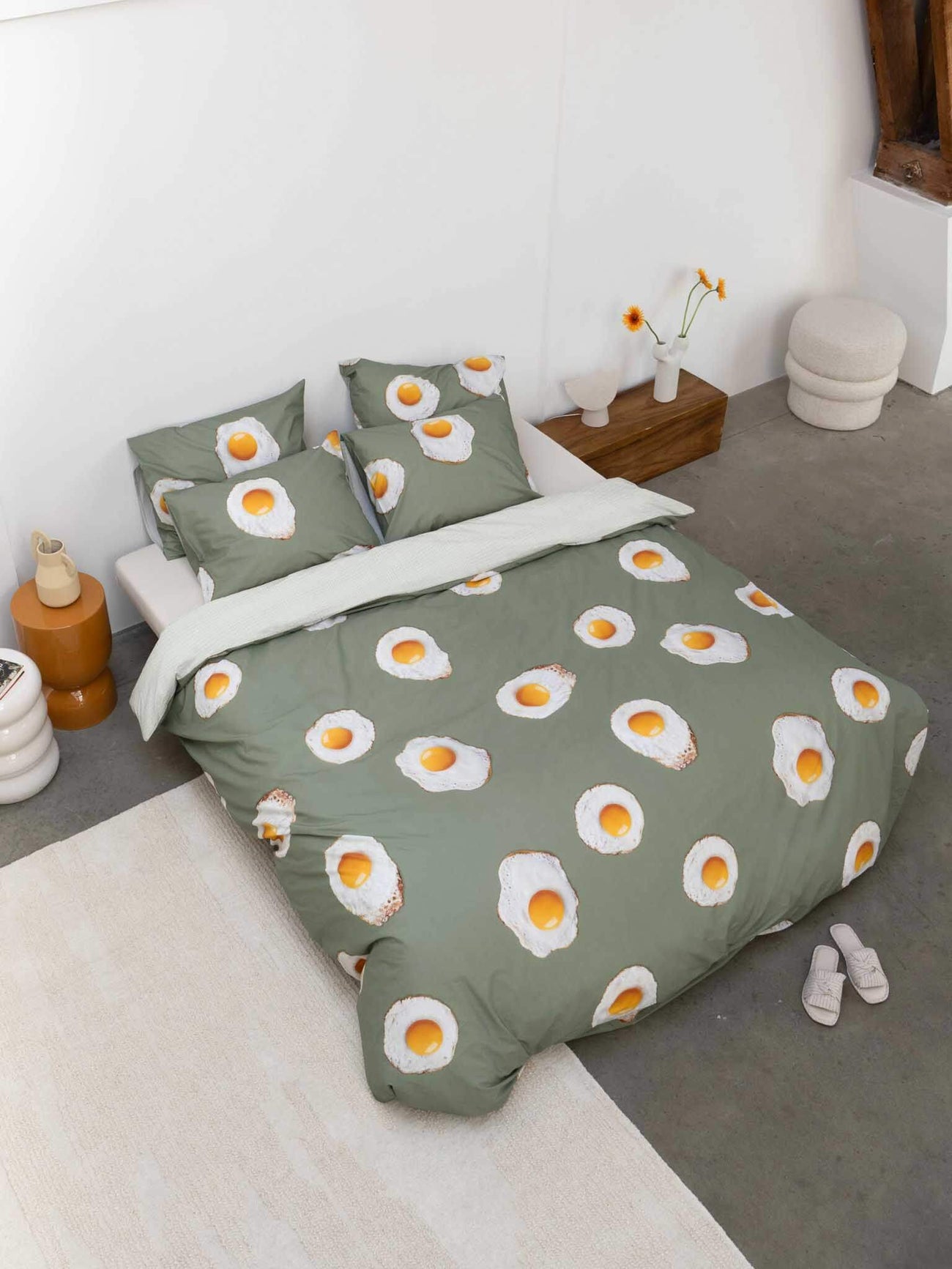 SNURK Eggs dekbedovertrek op bed met groene achtergrond en kussens met eieren, gemaakt van biologisch katoen.
