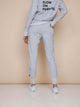 SNURK Grey Broek Regular Unisex, lichtgrijze joggingsbroek gedragen door vrouw, ideale outfit voor thuis of sport.