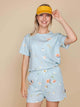 Vrouw in SNURK Hopeless Romantic Shorts Dames met bloemenprint en gele pet.