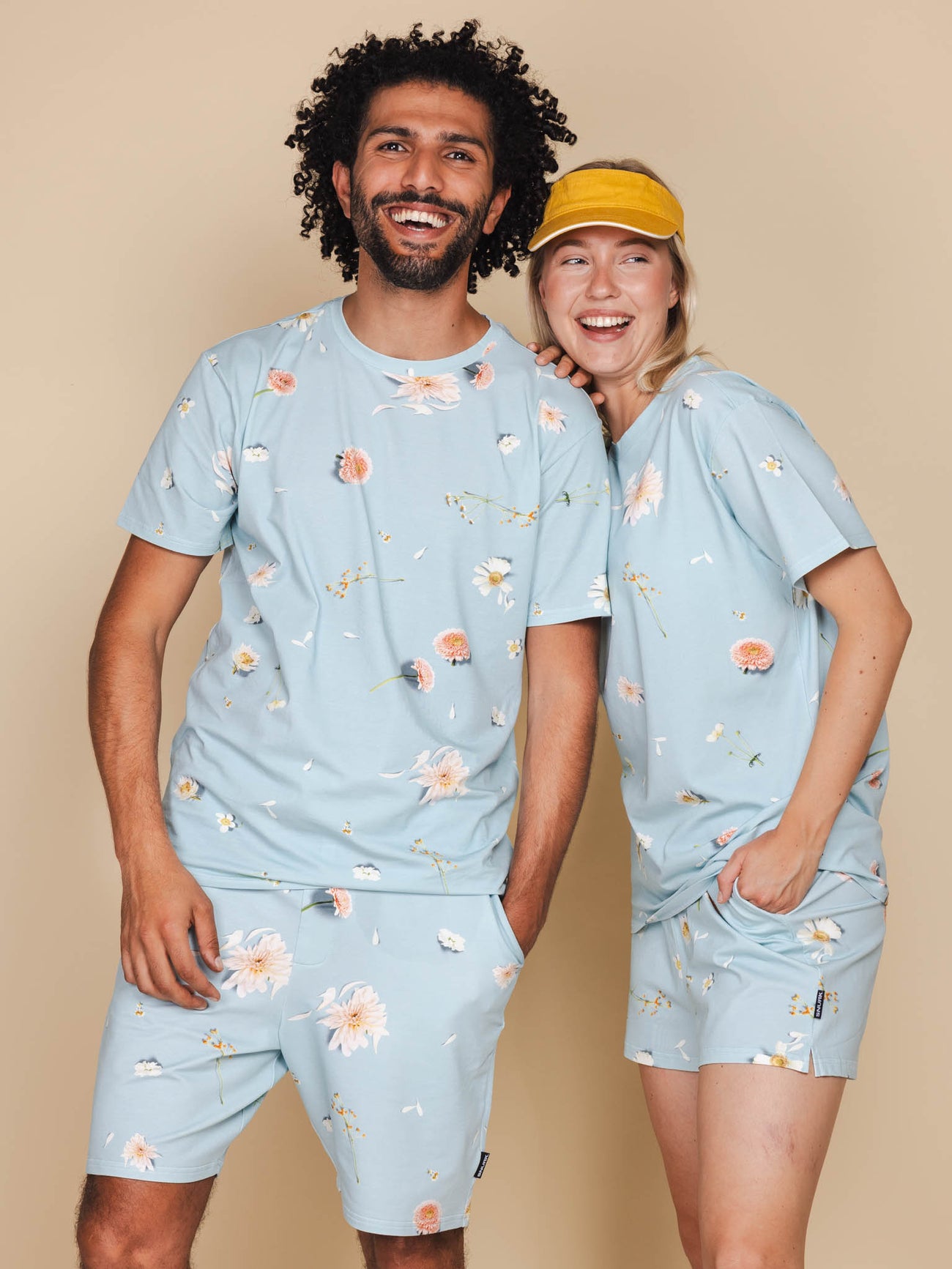 SNURK Hopeless Romantic T-shirt Unisex in zachte blauw met bloemenprint, gedragen door een man en een vrouw.