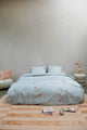SNURK Hopeless Romantic dekbedovertrek op een bed met bloemenprint en zachte accessoires.