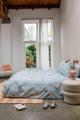 SNURK Hopeless Romantic dekbedovertrek op bed met bloemenprint in lichte slaapkamer.